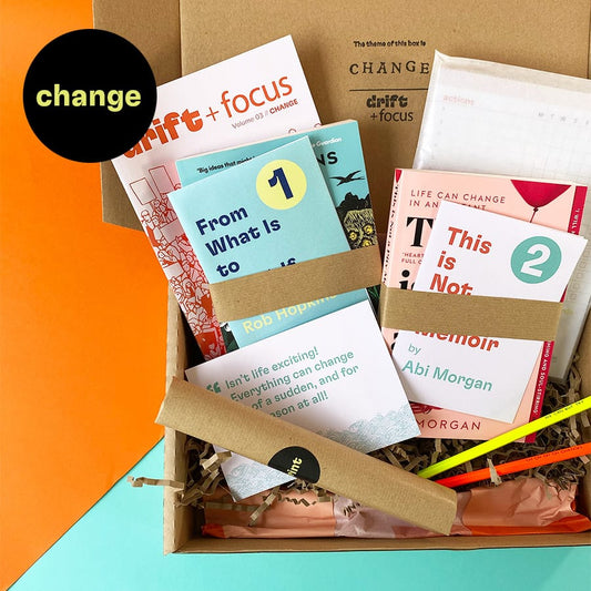 Open kraft box full of books, gifts and other reading curated around the theme change