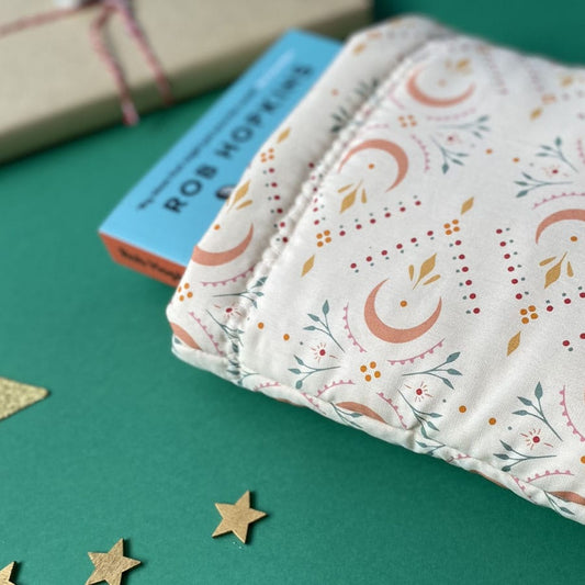 Close up of cream coloured padded book sleeve with subtle moon and leaf pattern