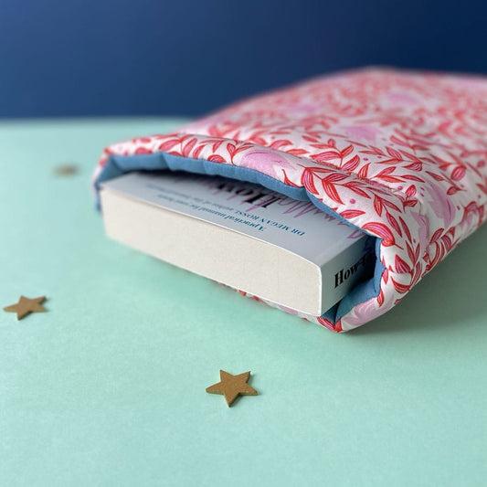 Close up of a pink and red patterned padded book sleeve holding a fat paperback